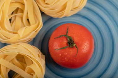 Mavi tabak taze domatesli çiğ tagliatelle yuvaları. Yüksek kalite fotoğraf