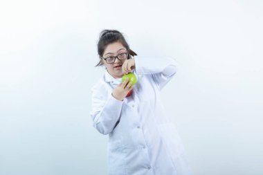 Doktor üniformalı genç bir kız elinde yeşil ve kırmızı elma meyveleri tutuyor. Yüksek kalite fotoğraf