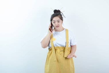 Genç ve güzel kız model ayakta duruyor ve beyaz duvara karşı cep telefonuyla konuşuyor. Yüksek kalite fotoğraf