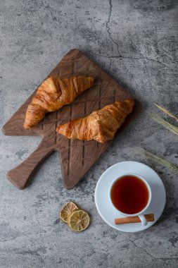 Tahta kesme tahtası, taze kruvasan ve bir fincan sıcak çay. Yüksek kalite fotoğraf