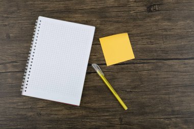 Ahşap zemin üzerinde kalem ve defter olan turuncu kare çıkartmalar. Yüksek kalite fotoğraf