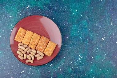Sağlıklı fındıklı kırmızı bir tabak ve galaksi arka planında lezzetli krakerler. Yüksek kalite fotoğraf