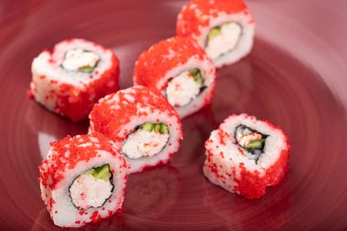 Kaliforniya suşisinin kırmızı tabağı doku arka planında yuvarlanıyor. Yüksek kalite fotoğraf