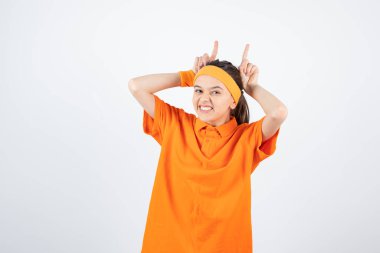 Hayali boynuzlarını gösteren turuncu elbiseli genç sporcunun portresi. Yüksek kalite fotoğraf