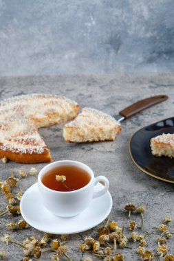Lezzetli bir parça kek ve beyaz bir fincan sıcak çay ile siyah bir tabak. Yüksek kalite fotoğraf