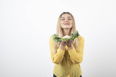 Gülümseyen güzel bir kadın modelin elinde karnabahar tutarken fotoğrafı. Yüksek kalite fotoğraf