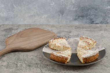 Tahtanın etrafına hindistan cevizi parçacıkları serpiştirilmiş lezzetli kek dilimleri. Yüksek kalite fotoğraf