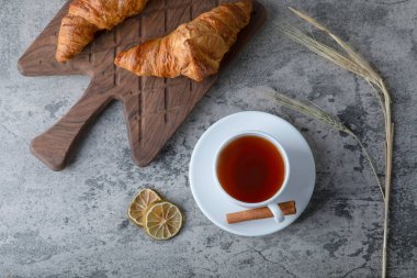 Tahta kesme tahtası, taze kruvasan ve bir fincan sıcak çay. Yüksek kalite fotoğraf