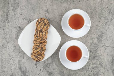 Üzerine tohum serpiştirilmiş taze yulaf ezmeli kurabiyeler ve iki fincan siyah çay. Yüksek kalite fotoğraf