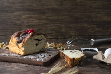 Masaya yerleştirilmiş haşhaş tohumlu ahşap bir turta ve tavuk yumurtası.