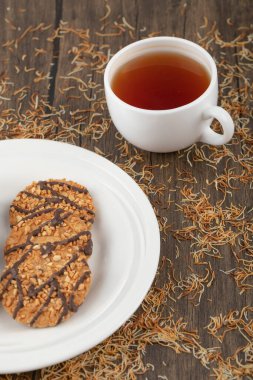 Tohumlu bir tabak kurabiye ve ahşap masaya bir fincan siyah çay. Yüksek kalite fotoğraf