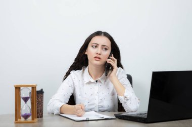 İş kadını masada oturuyor ve cep telefonuyla konuşuyor. Yüksek kalite fotoğraf