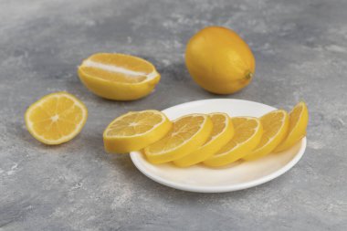Mermer zemin üzerinde taze limon dilimleri olan beyaz bir tabak. Yüksek kalite fotoğraf