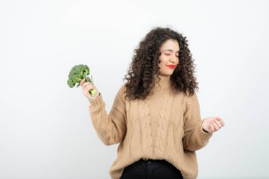 Örgü süveter giymiş güzel bir kadın sağlıklı brokoli tutuyor. Yüksek kalite fotoğraf