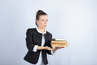 Beyaz arka plan üzerine kitapları tutmaya çalışan genç bir öğrenci görüntüsü. Yüksek kalite fotoğraf