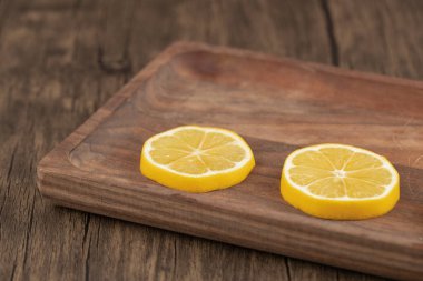 Ahşap zemin üzerinde ahşap tepside iki limon dilimi. Yüksek kalite fotoğraf