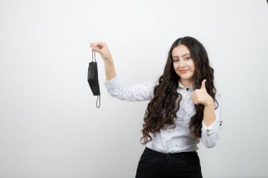 Siyah maske takan ve baş parmak kaldıran genç bir kadın resmi. Yüksek kalite fotoğraf
