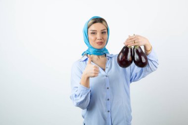 Pretty woman in handkerchief with eggplants showing thumb up . High quality photo
