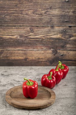 Wooden plate of ripe red bell peppers on stone surface. High quality photo