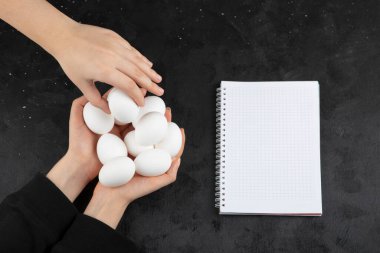 El, siyah arka plandaki kadın ellerinden çiğ beyaz yumurta alıyor. Yüksek kalite fotoğraf