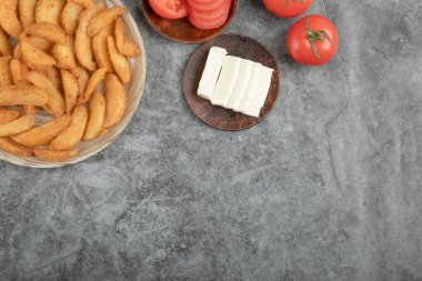 Taş zeminde kızarmış patates dilimleri ve domatesler seramik tabakta. Yüksek kalite fotoğraf