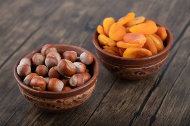 Tahta bir masaya yerleştirilmiş sağlıklı fındık ve kurutulmuş kayısı meyveleriyle dolu kaseler. Yüksek kalite fotoğraf