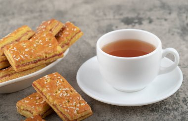 Taş bir masanın üzerine kraker konmuş beyaz fincan sıcak çay. Yüksek kalite fotoğraf