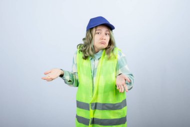 Üniformalı genç bayan mimar, beyaz duvarın arkasında üzgün bir ifadeyle dikiliyor. Yüksek kalite fotoğraf