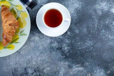 Taze ve lezzetli kruvasan ve bir fincan sıcak çay. Yüksek kalite fotoğraf