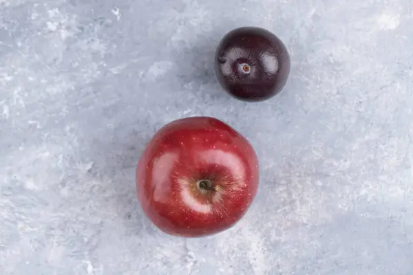 Ganze Frische Pflaumenfrüchte Mit Einem Roten Apfel Auf Einem Marmorhintergrund — Stockfoto