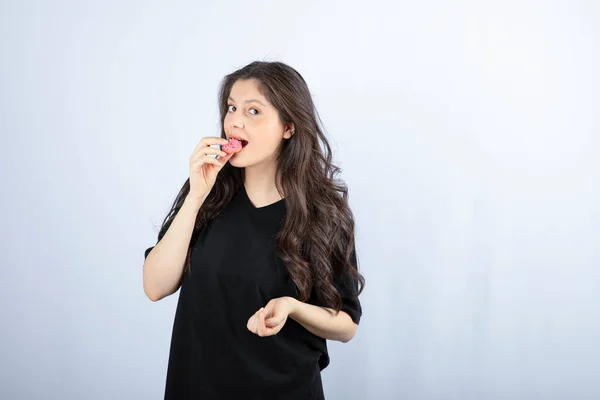 Menina Roupa Preta Comendo Biscoito Rosa Fundo Branco Foto Alta — Fotografia de Stock