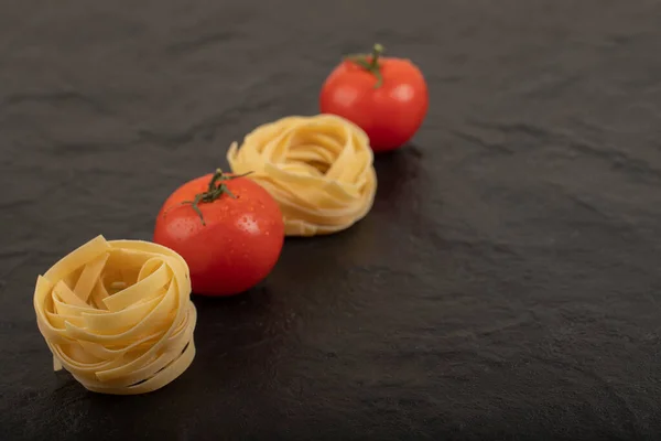 Raw Tagliatelle Nests Fresh Tomatoes Black Surface High Quality Photo — Stock Photo, Image