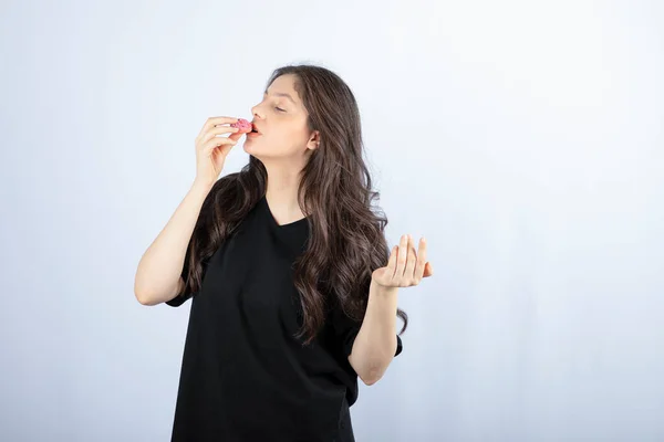 Menina Roupa Preta Comendo Biscoito Rosa Fundo Branco Foto Alta — Fotografia de Stock