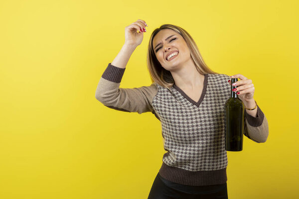 Image of young woman holding bottle of wine and standing. High quality photo