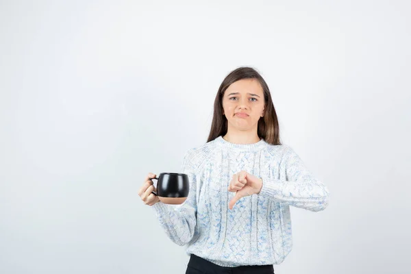 Młoda Kobieta Trzyma Filiżankę Gorącej Kawy Pokazuje Kciuk Dół Wysokiej — Zdjęcie stockowe