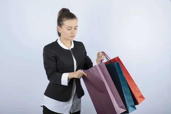 Beyaz Arka Planda Alışveriş Torbalarının Içine Bakan Genç Bir Kadın — Stok fotoğraf