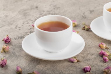 Taş yüzeyinde kurumuş güller olan siyah sıcak çay fincanları. Yüksek kalite fotoğraf