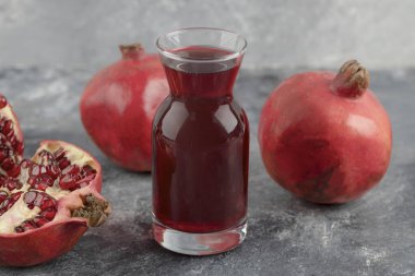 Bir bardak taze meyve suyu ve mermer arka planda lezzetli nar meyveleri. Yüksek kalite fotoğraf