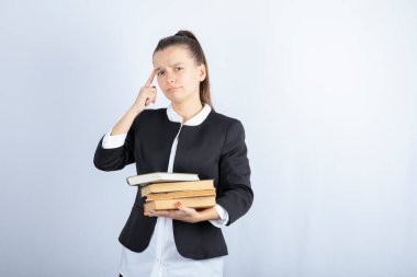 Beyaz arka plan üzerine düşünen bir sürü kitabı olan genç bir öğrenci. Yüksek kalite fotoğraf