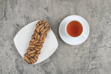 Taze pişmiş yulaflı kurabiyeler serpiştirilmiş tohumlar ve bir fincan siyah çay. Yüksek kalite fotoğraf