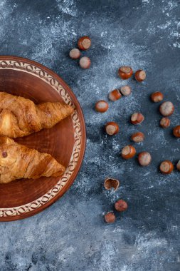 Taze kruvasan ve sağlıklı macadamia fındıklı yuvarlak bir tabak. Yüksek kalite fotoğraf