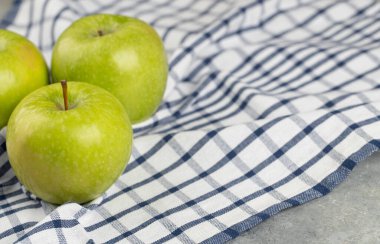 Çizgili masa örtüsüne yerleştirilmiş lezzetli yeşil elmalar. Yüksek kalite fotoğraf