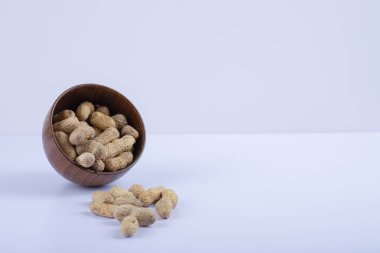 Beyaz arka planda soyulmamış fıstıklarla dolu ahşap bir kase. Yüksek kalite fotoğraf