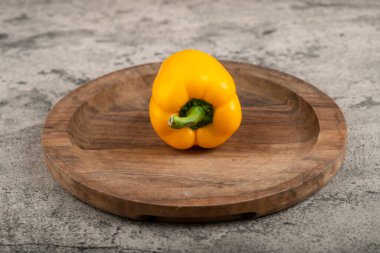 Yellow sweet bell pepper placed on wooden plate. High quality photo