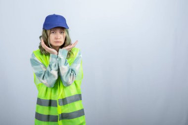 Üniformalı genç bayan mimar, beyaz duvarın arkasında üzgün bir ifadeyle dikiliyor. Yüksek kalite fotoğraf