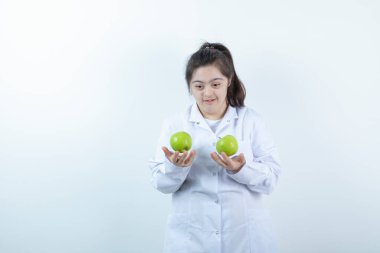 Doktor üniformalı genç bir kız elinde yeşil elma meyveleri tutuyor. Yüksek kalite fotoğraf