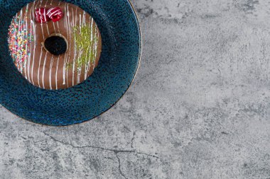 Çilekli çikolatalı donut ve mermer yüzeyine serpiştirilmiş mavi tabak. Yüksek kalite fotoğraf