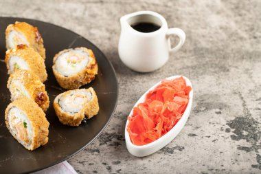 Philadelphia 'nın siyah tabağı ve masada sıcak suşi ruloları. Yüksek kalite fotoğraf