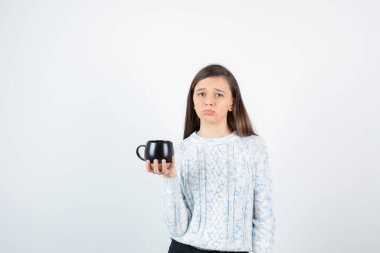 Beyaz bir duvarın üzerinde elinde bir fincan sıcak kahve tutan genç bir kadın. Yüksek kalite fotoğraf