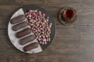 Kurutulmuş güller ve bir fincan çayla dolu bir tabak çikolata kremalı rulo. Yüksek kalite fotoğraf